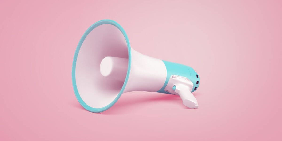 White megaphone laying on a pink background