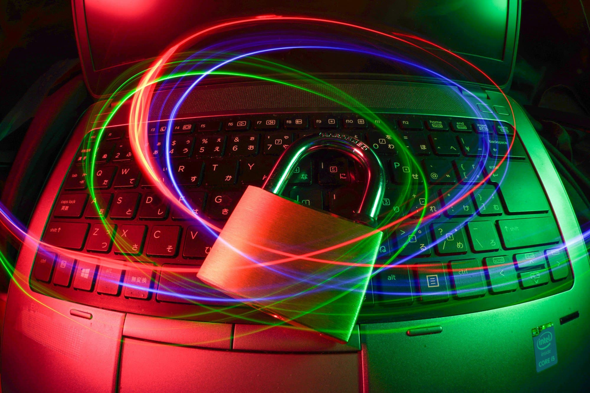 A padlock sits on a laptop keyboard, surrounded by colorful light trails, symbolizing cybersecurity, data protection, and the importance of an IT security audit.