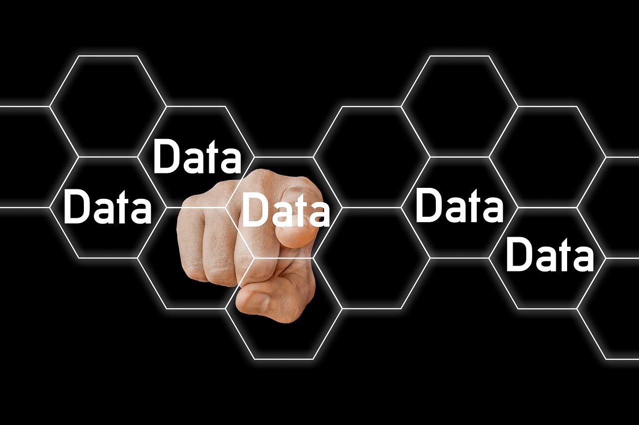 A hand points forward, touching a virtual honeycomb grid with the word Data repeated in several hexagons on a black background, highlighting the concept of Data Minimization.